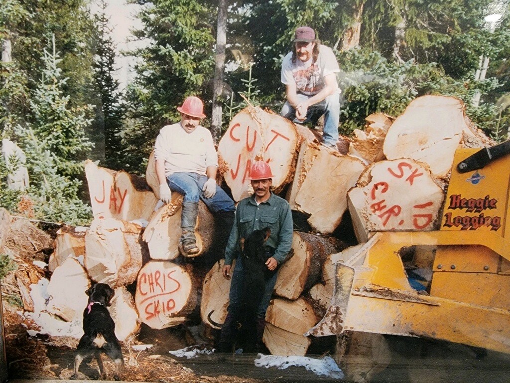 men standing by a pile of logs